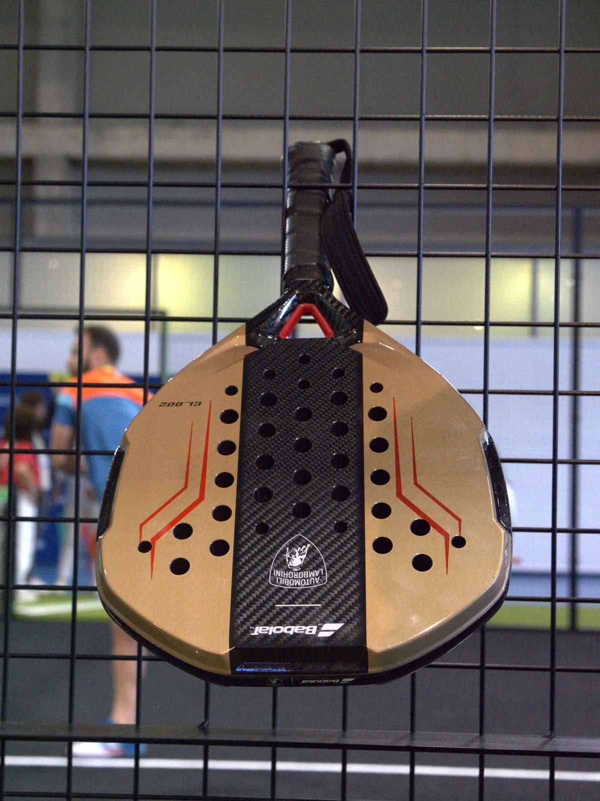 Pala de pádel colgada en la malla de una pista.